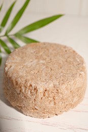 Photo of Solid shampoo bar on white wooden table, closeup