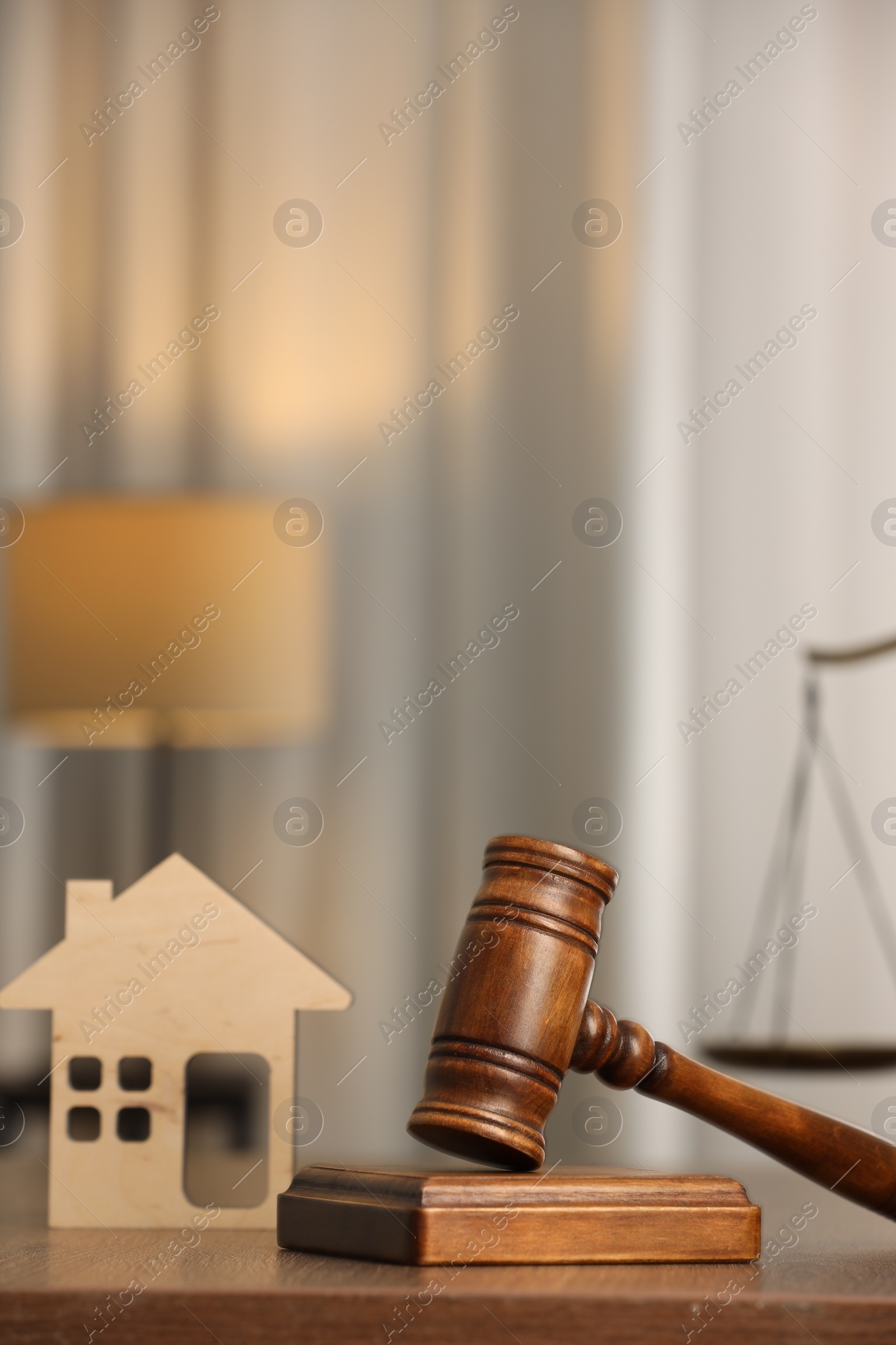 Photo of Law concept. Gavel and figure of house on wooden table, space for text