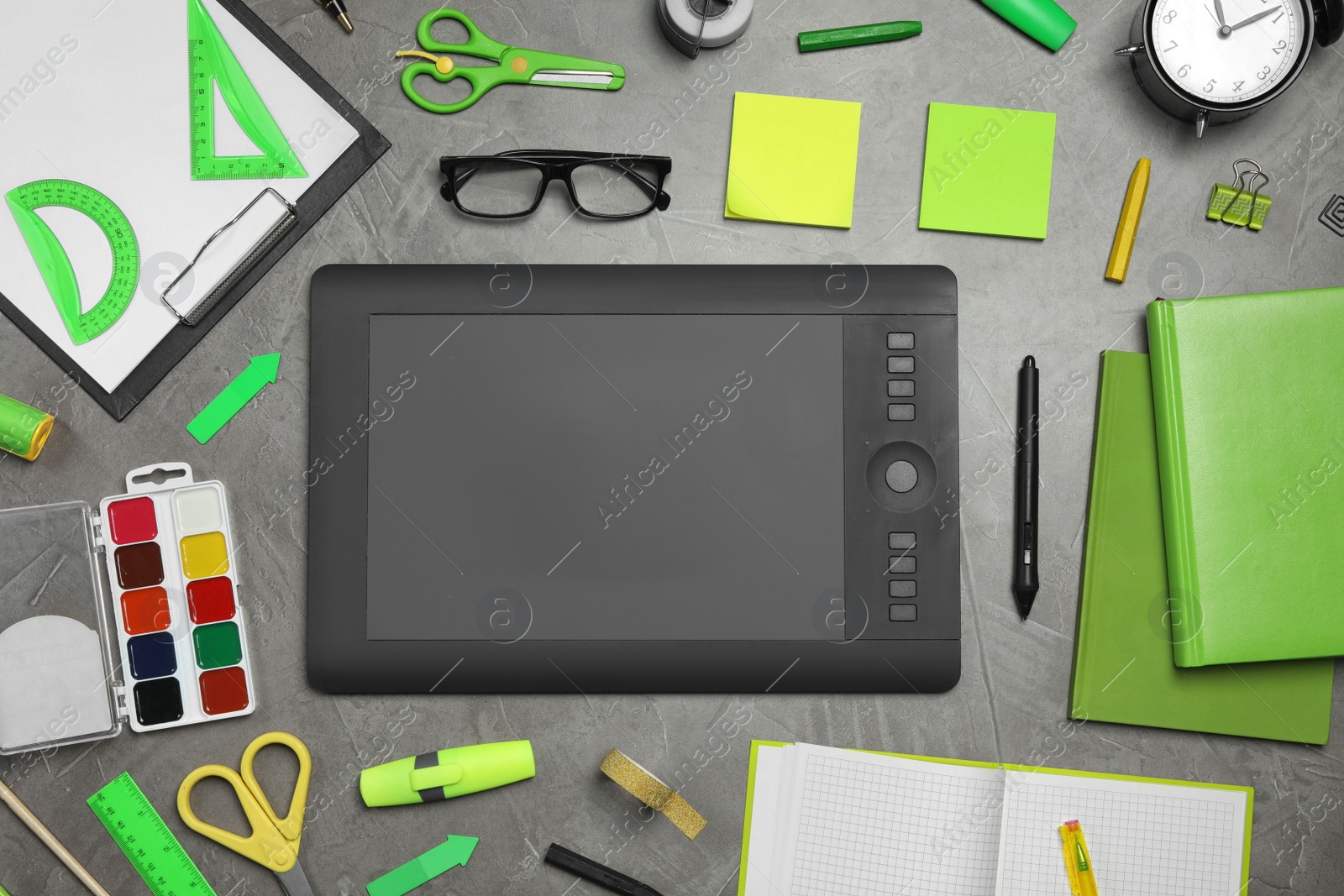 Photo of Flat lay composition with graphic drawing tablet and different office items on grey stone background. Designer's workplace