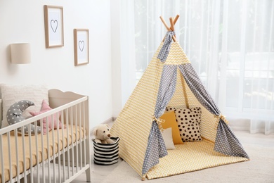 Photo of Cozy baby room interior with play tent and crib