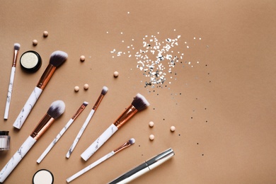 Photo of Flat lay composition with makeup brushes on brown background. Space for text
