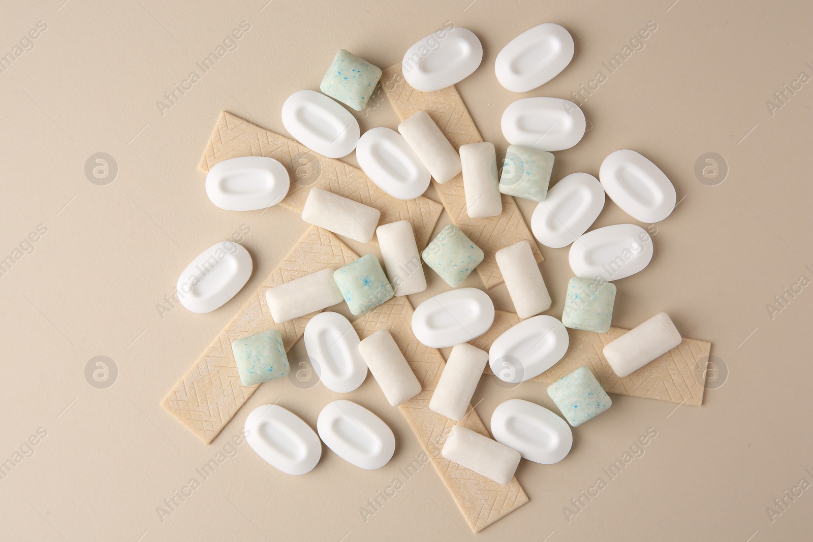 Photo of Many different chewing gums on beige background, flat lay