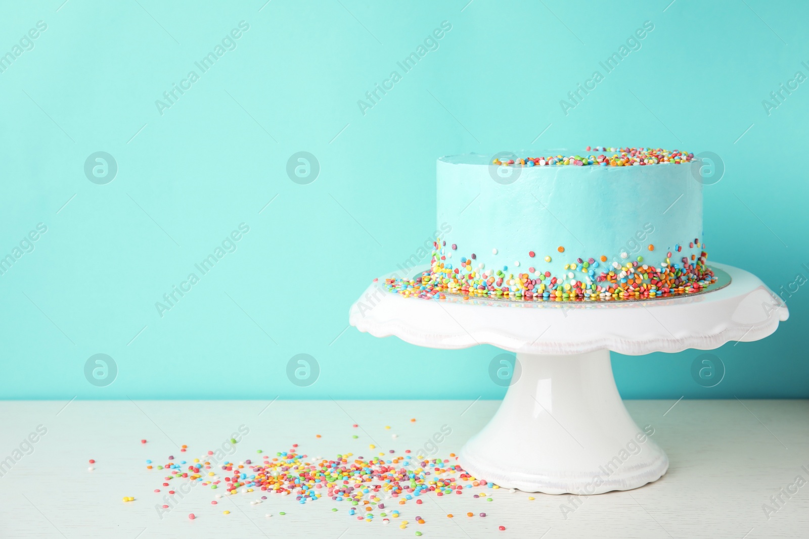 Photo of Fresh delicious birthday cake on stand against color background. Space for text