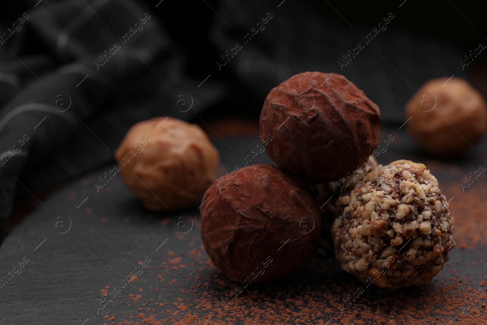 Photo of Different tasty chocolate candies on slate plate, closeup