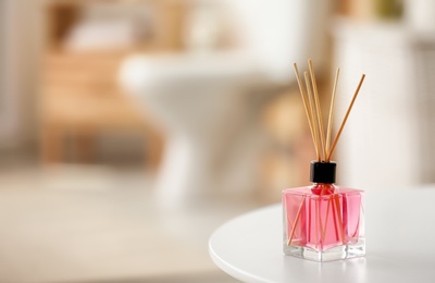 Photo of Aromatic reed air freshener on table against blurred background