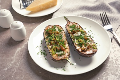 Plate with tasty stuffed eggplants on gray table