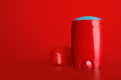 Stick deodorant on table against red background. Space for design