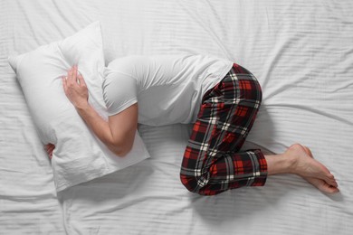 Photo of Man covering his head with pillow on bed, top view. Insomnia problem
