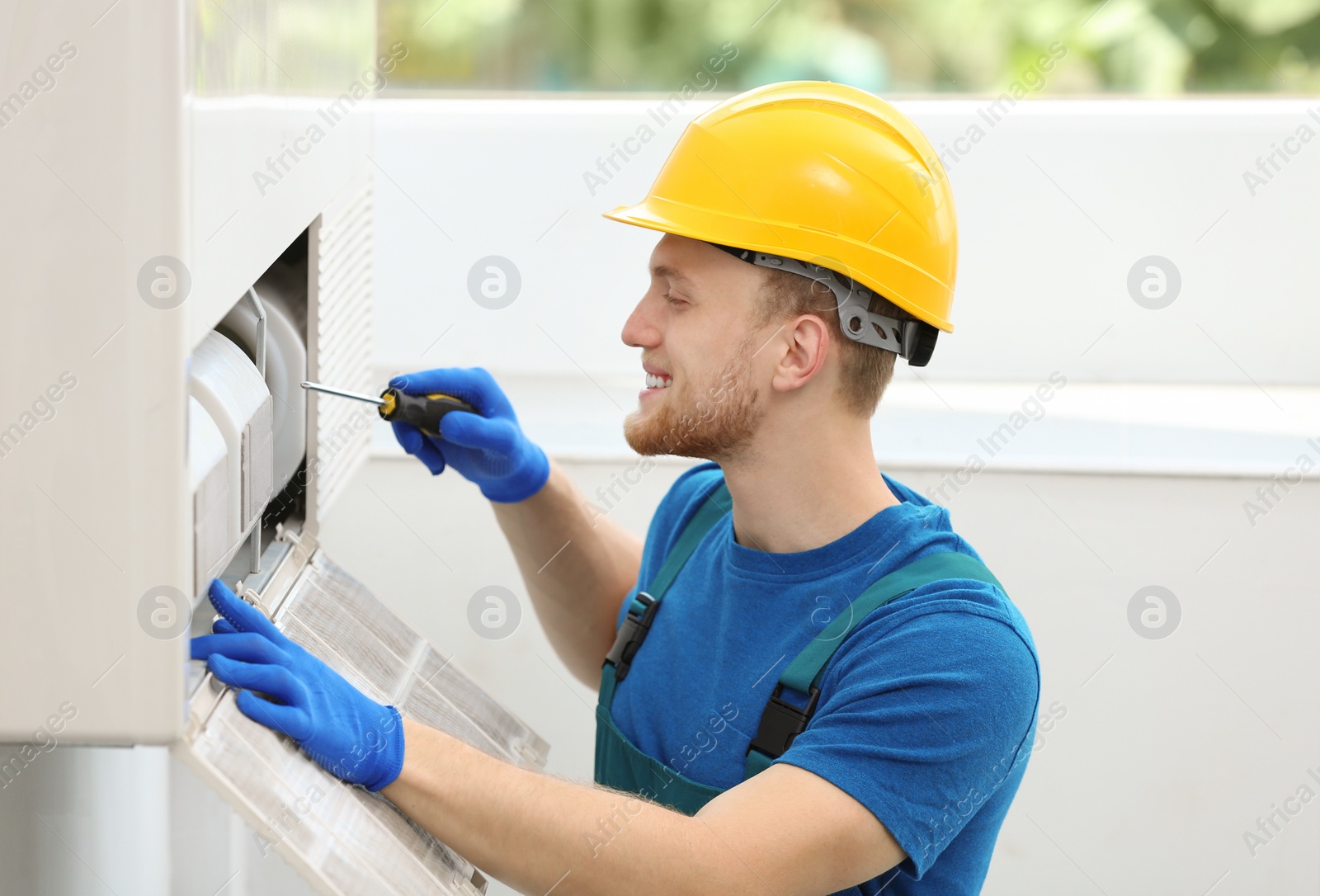 Photo of Professional technician maintaining modern air conditioner indoors