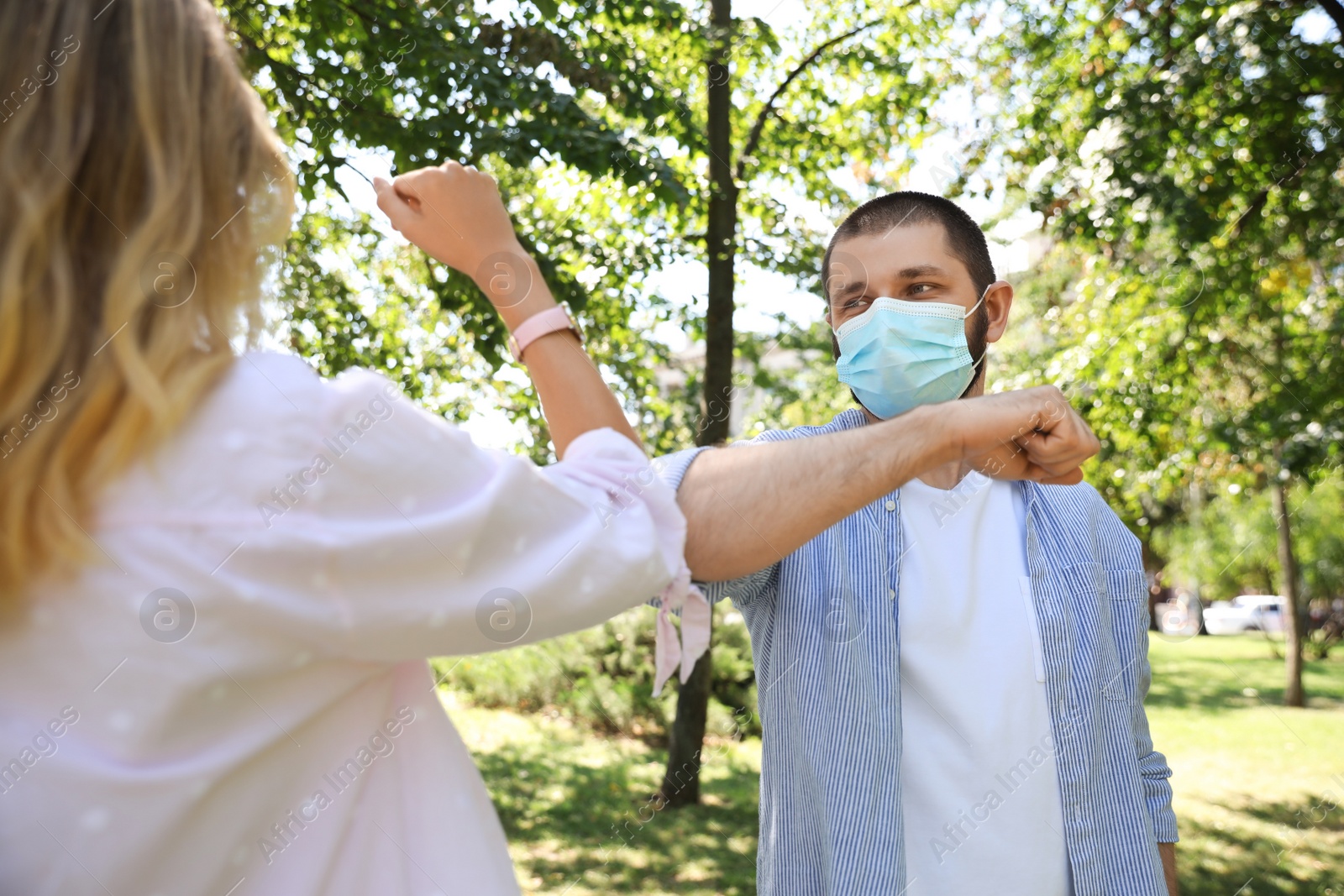 Photo of Man and woman bumping elbows to say hello outdoors. Keeping social distance during coronavirus pandemic