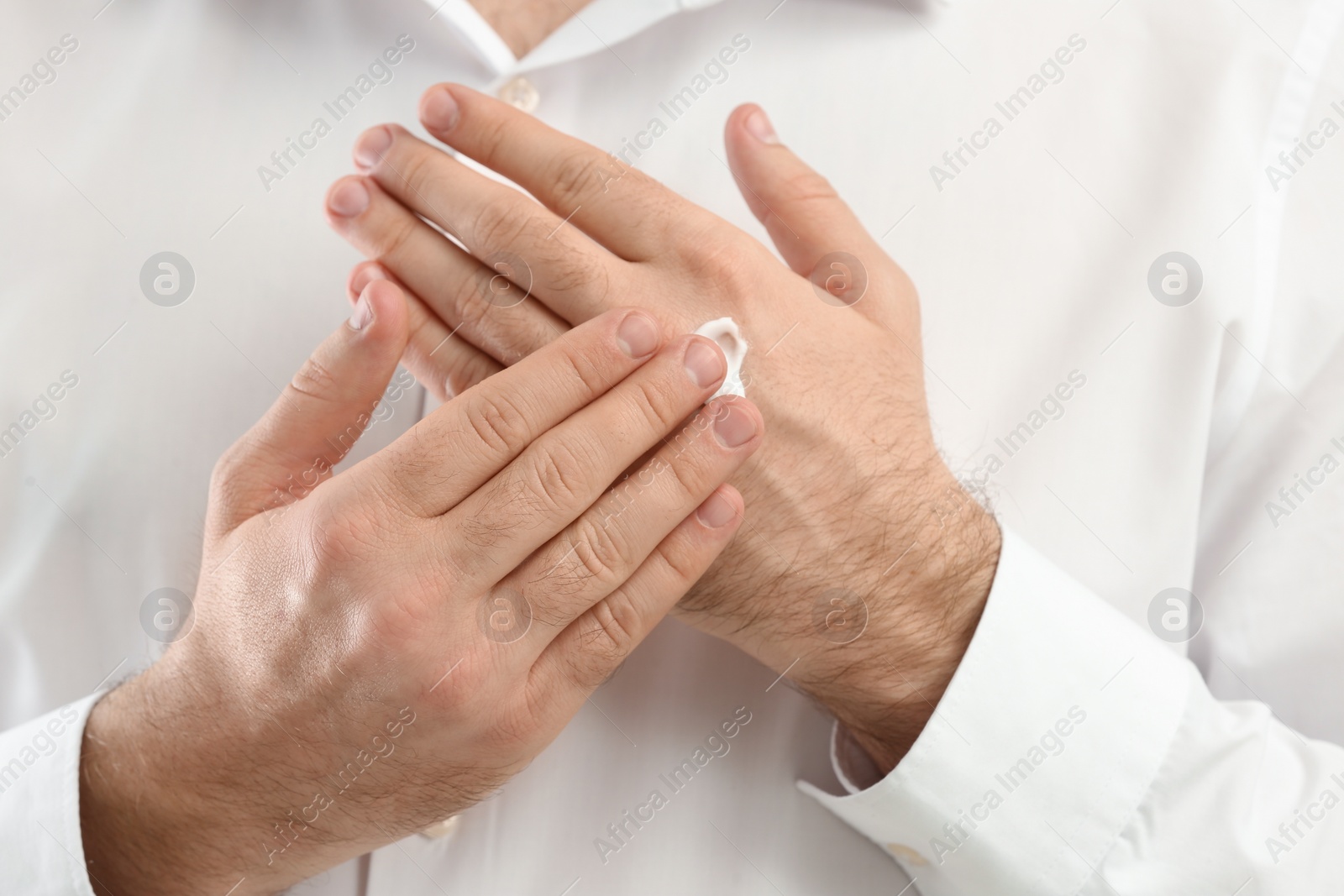 Photo of Man applying moisturizing cream onto hand, closeup