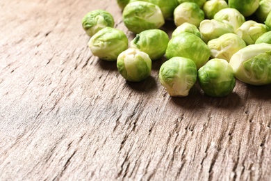 Photo of Fresh Brussels sprouts on wooden table, closeup. Space for text