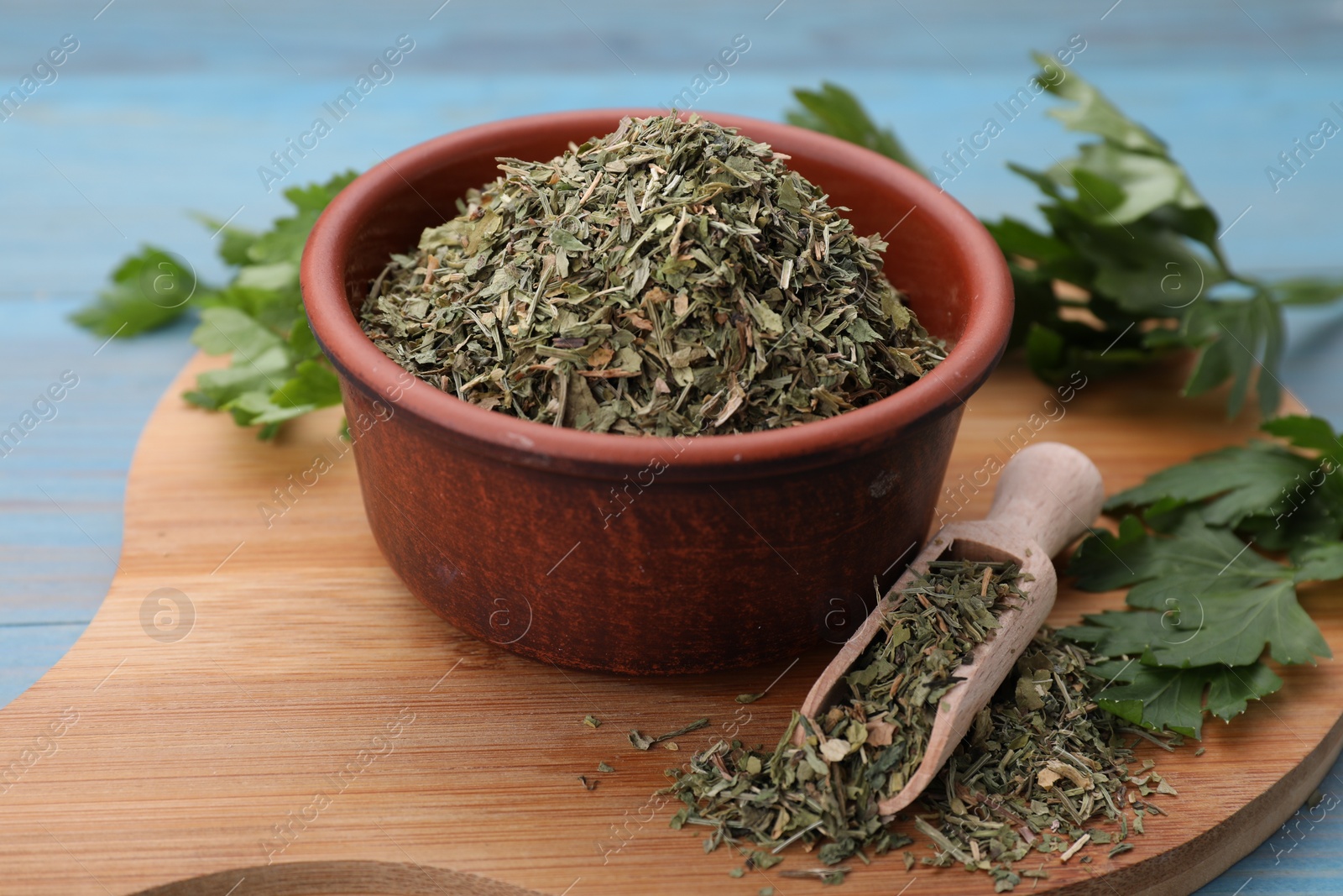 Photo of Dried parsley and fresh leaves on light blue table, closeup