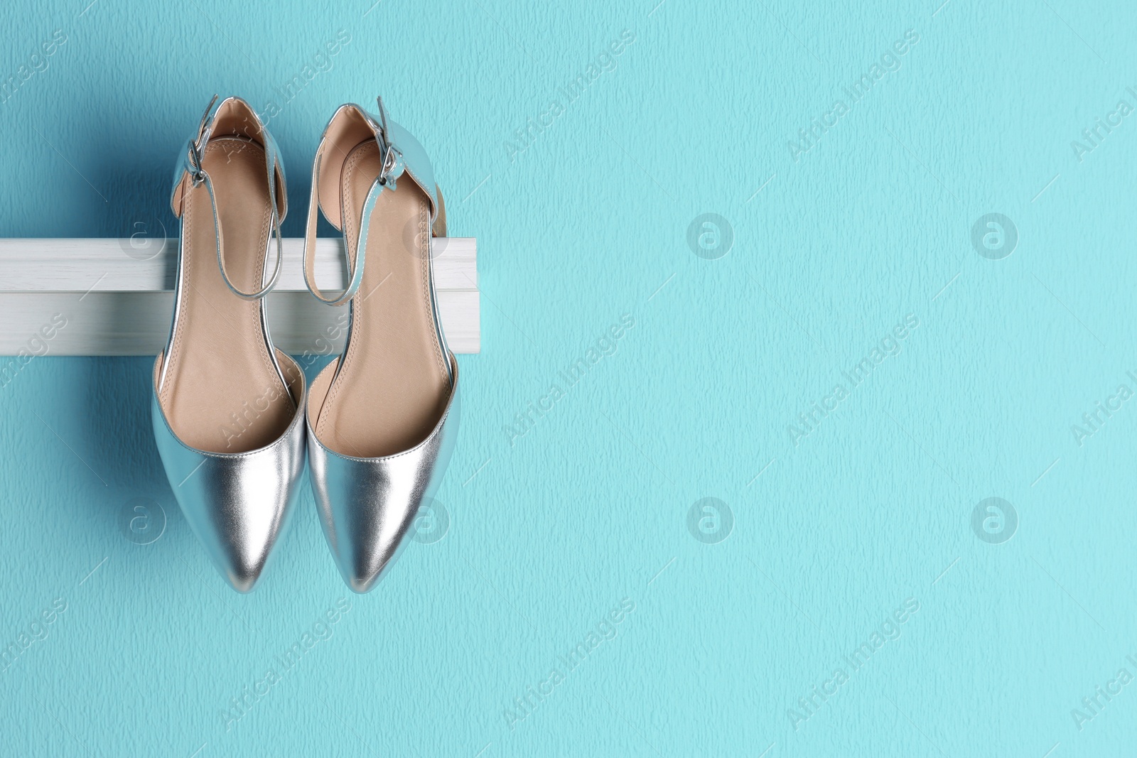 Photo of Pair of female shoes on shelf against color background