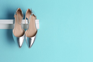 Pair of female shoes on shelf against color background