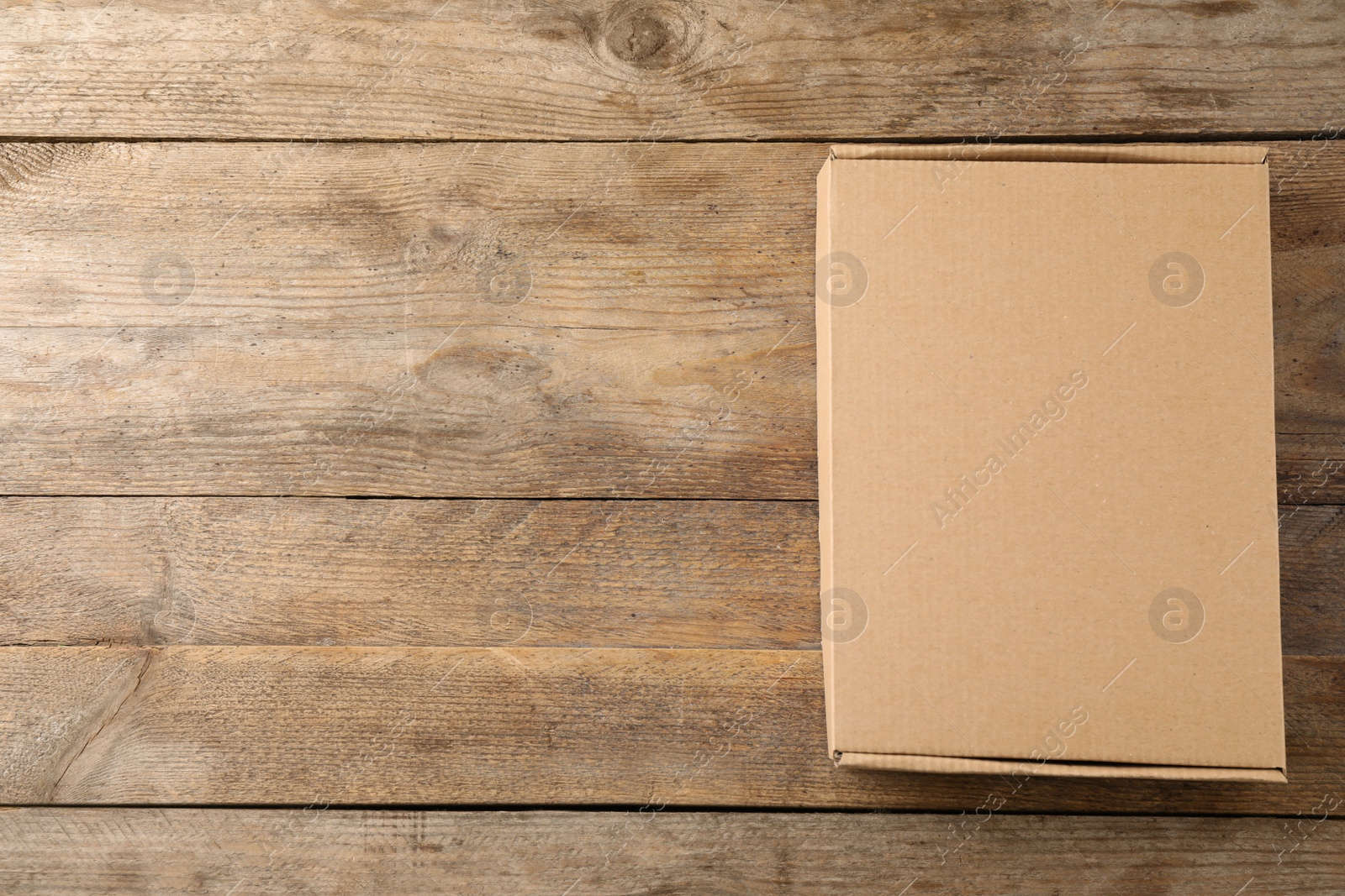 Photo of Closed cardboard box on wooden background, top view. Space for text