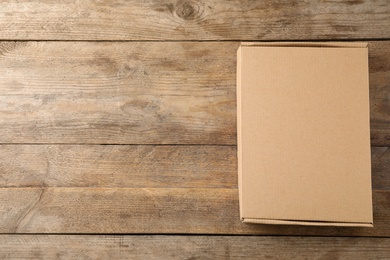 Photo of Closed cardboard box on wooden background, top view. Space for text