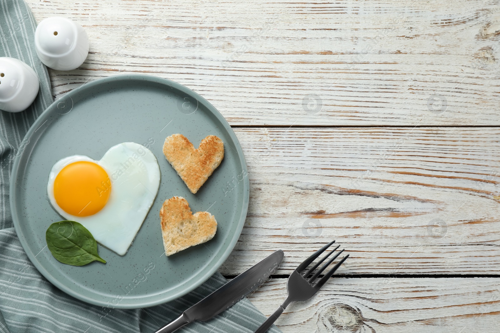 Photo of Romantic breakfast with heart shaped fried egg and toasts on white wooden table, flat lay. Space for text