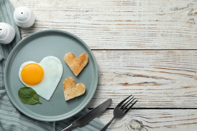 Photo of Romantic breakfast with heart shaped fried egg and toasts on white wooden table, flat lay. Space for text