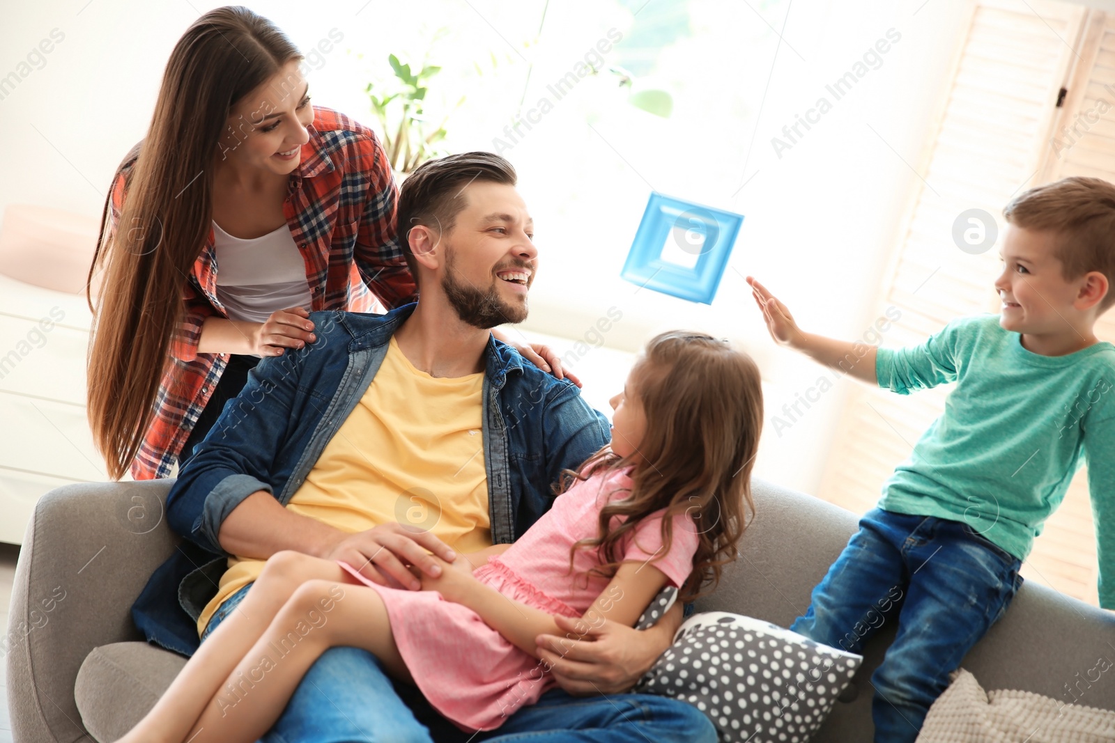 Photo of Young couple spending time with children at home. Happy family