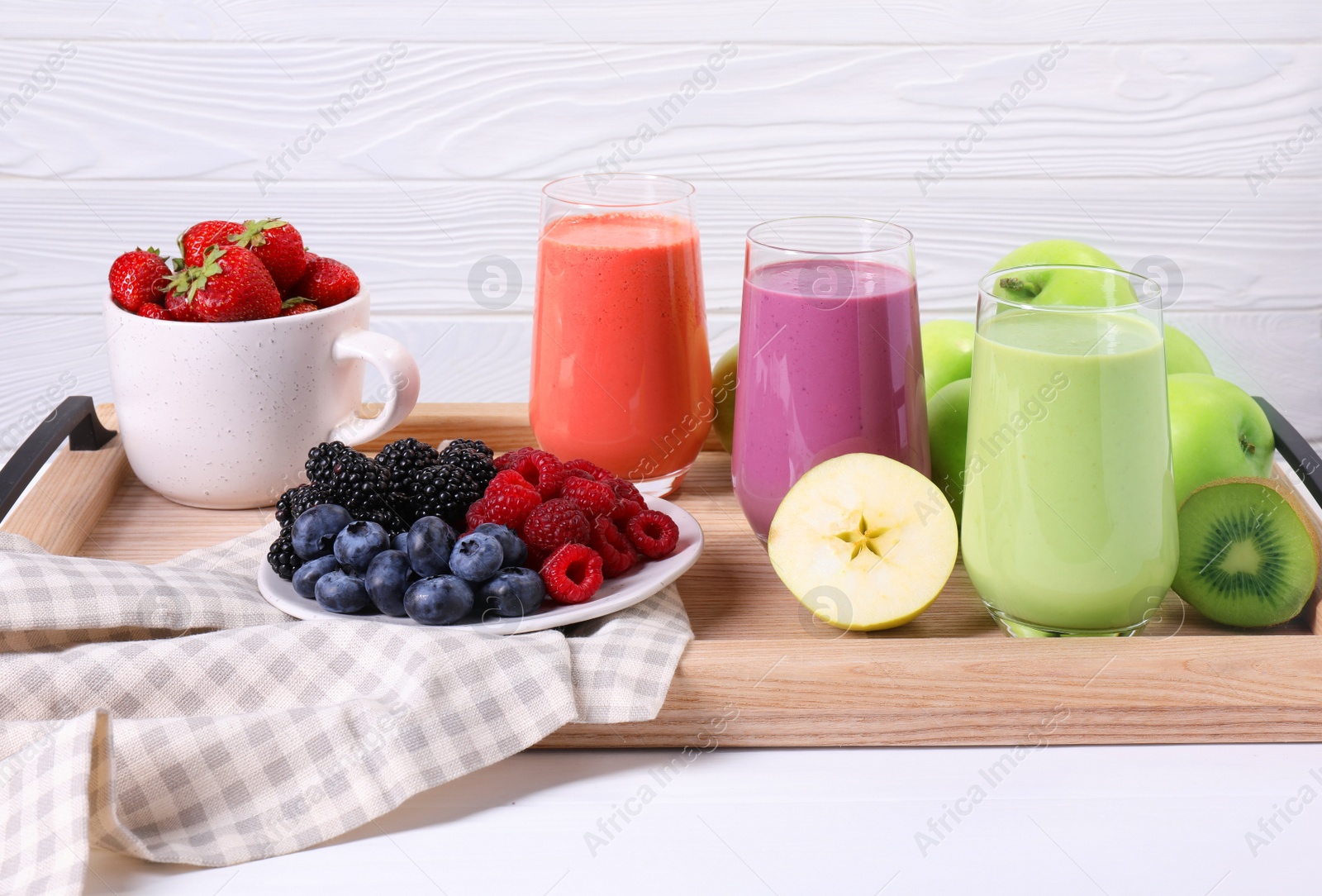 Photo of Glasses of different tasty smoothies and fresh ingredients on white wooden table