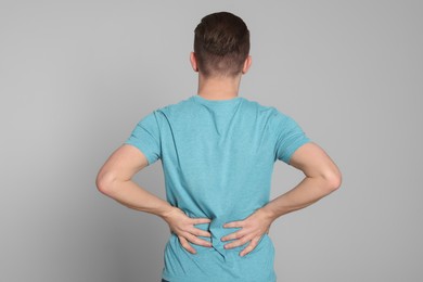 Photo of Man suffering from back pain on light grey background. Arthritis symptoms