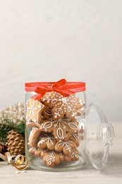 Photo of Tasty Christmas cookies in glass jar and festive decor on beige wooden table