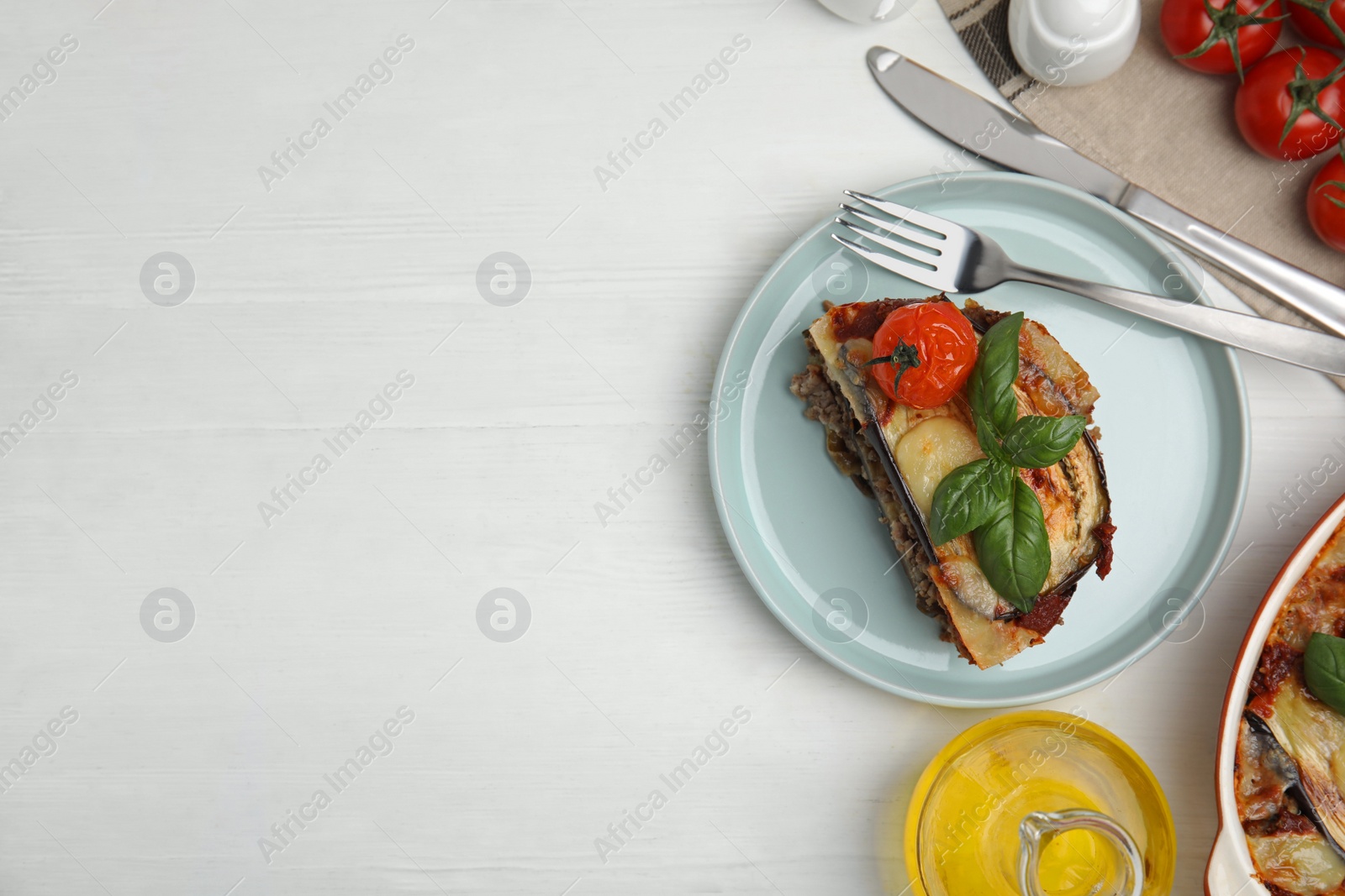 Photo of Plate of delicious eggplant lasagna served on white wooden table, flat lay. Space for text