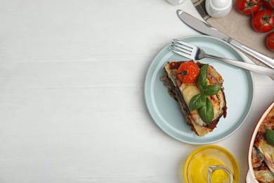 Photo of Plate of delicious eggplant lasagna served on white wooden table, flat lay. Space for text