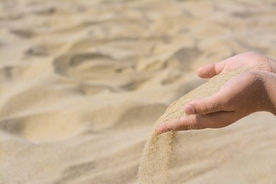 Photo of Child pouring sand from hand outdoors, closeup with space for text. Fleeting time concept