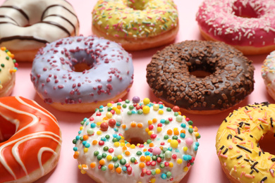 Photo of Delicious glazed donuts on pink background, closeup