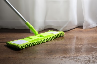 Photo of Cleaning parquet floor with mop, closeup. Space for text