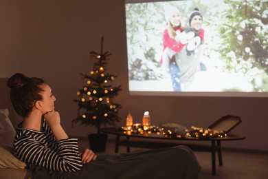 Woman watching romantic Christmas movie via video projector at home