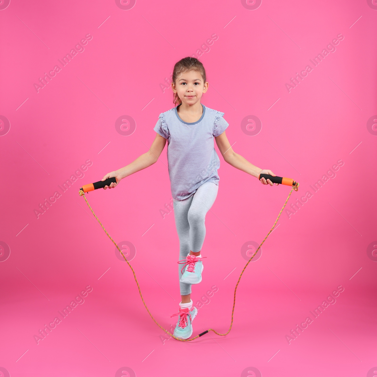 Photo of Full length portrait of girl jumping rope on color background