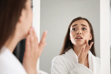 Photo of Emotional woman with beautiful eyelashes looking in mirror indoors