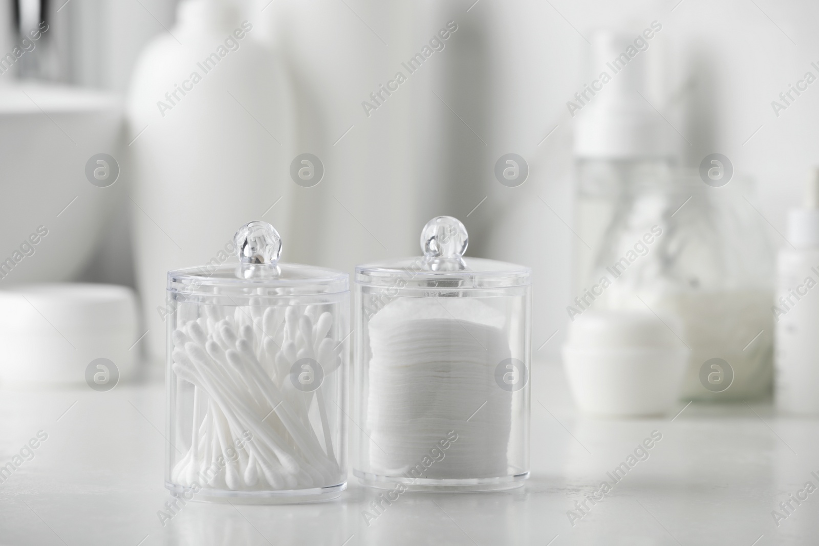 Photo of Containers with cotton swabs and pads on white countertop in bathroom