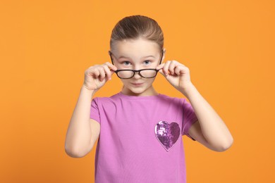 Photo of Portrait of cute girl in glasses on orange background