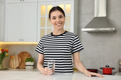Photo of Woman with glass of water at countertop in kitchen
