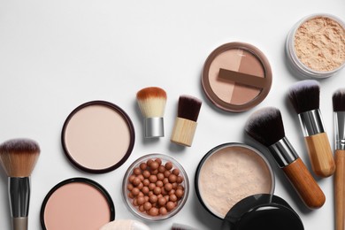 Photo of Different face powders and makeup brushes on light background, flat lay