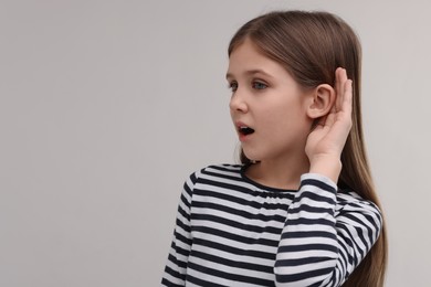 Photo of Little girl with hearing problem on grey background, space for text