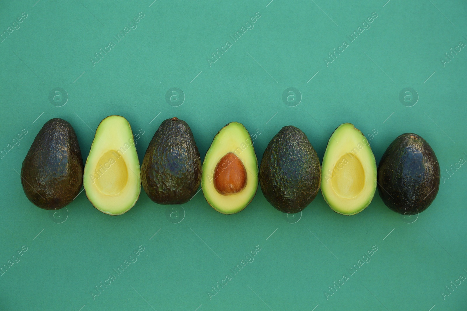 Photo of Tasty whole and cut avocados on turquoise background, flat lay