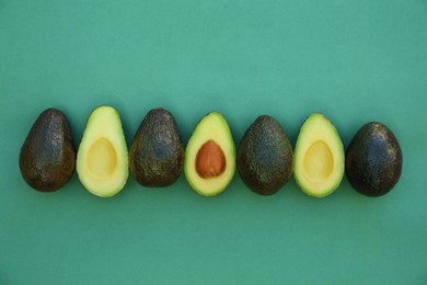 Photo of Tasty whole and cut avocados on turquoise background, flat lay