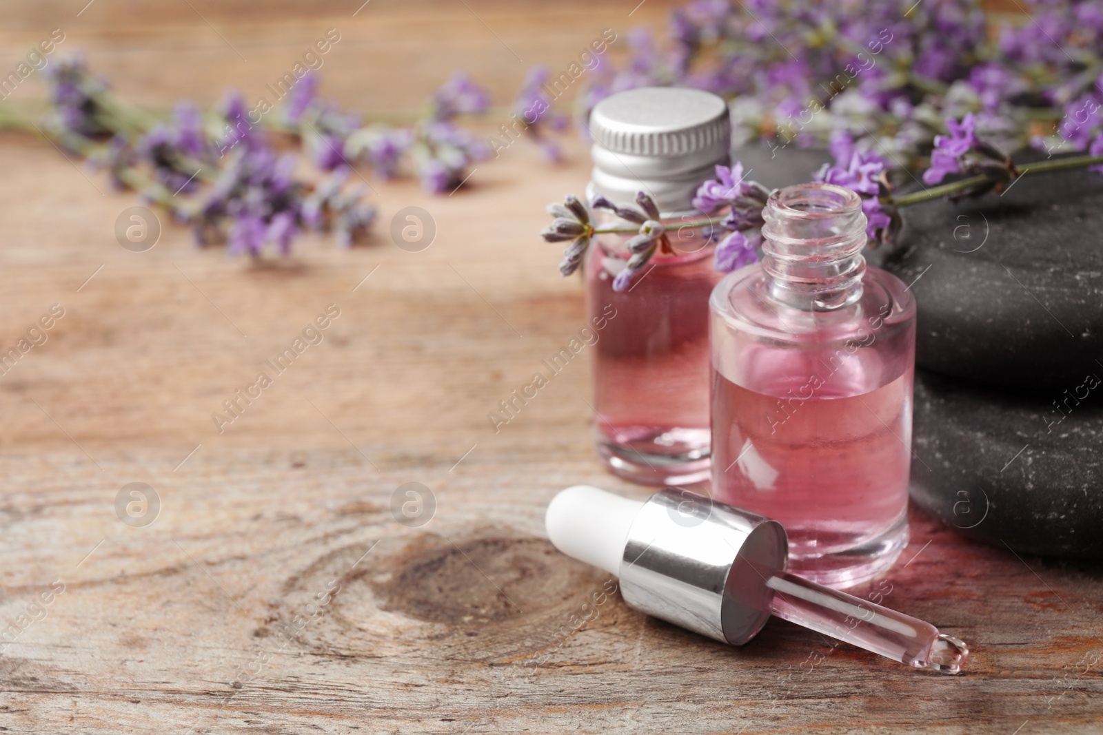 Photo of Bottles with natural lavender essential oil on wooden background. Space for text