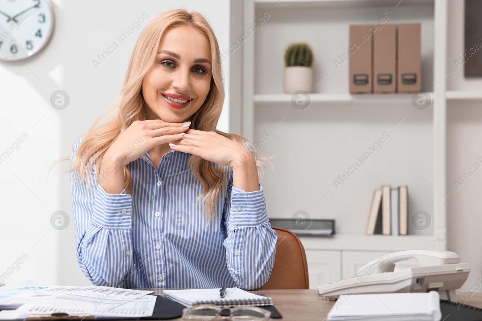 Photo of Happy secretary at table with stationery in office