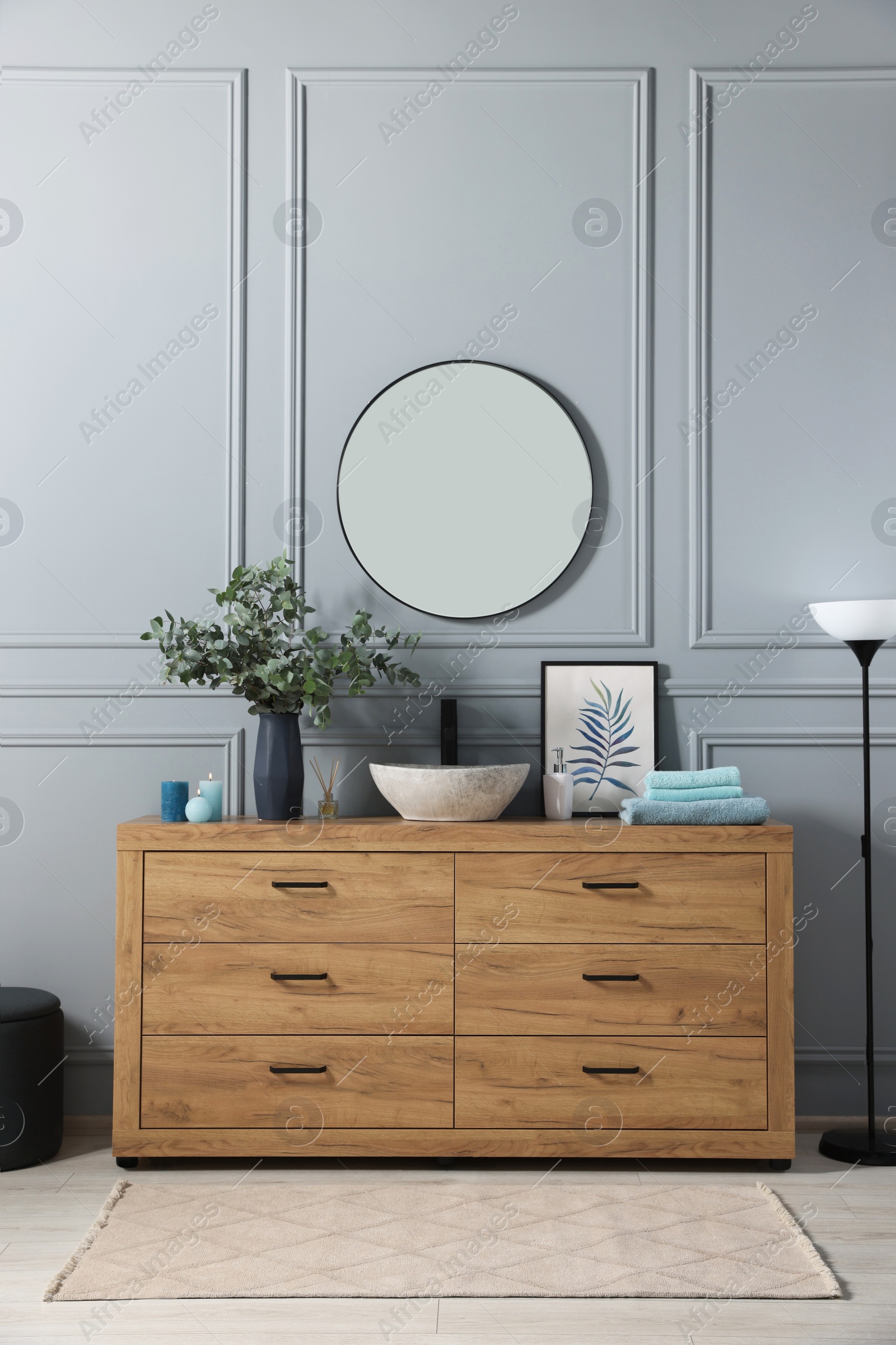 Photo of Modern bathroom interior with stylish mirror, eucalyptus branches, vessel sink and wooden vanity