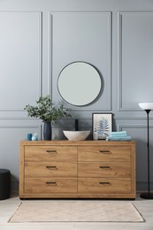 Photo of Modern bathroom interior with stylish mirror, eucalyptus branches, vessel sink and wooden vanity