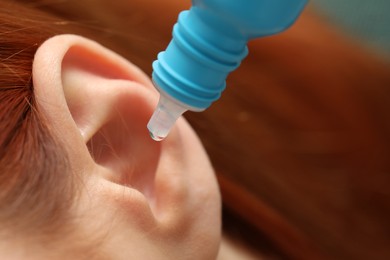 Photo of Woman applying medical ear drops, macro view