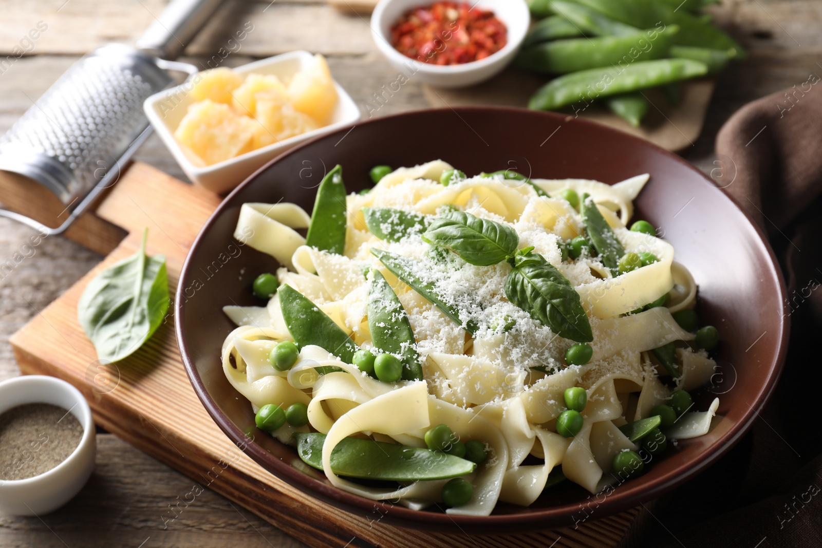 Photo of Delicious pasta with green peas and ingredients on wooden table