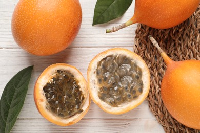 Delicious ripe granadillas on white wooden table, flat lay