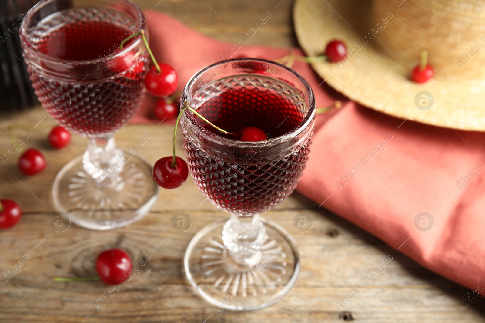 Photo of Delicious cherry wine with ripe juicy berries on wooden table